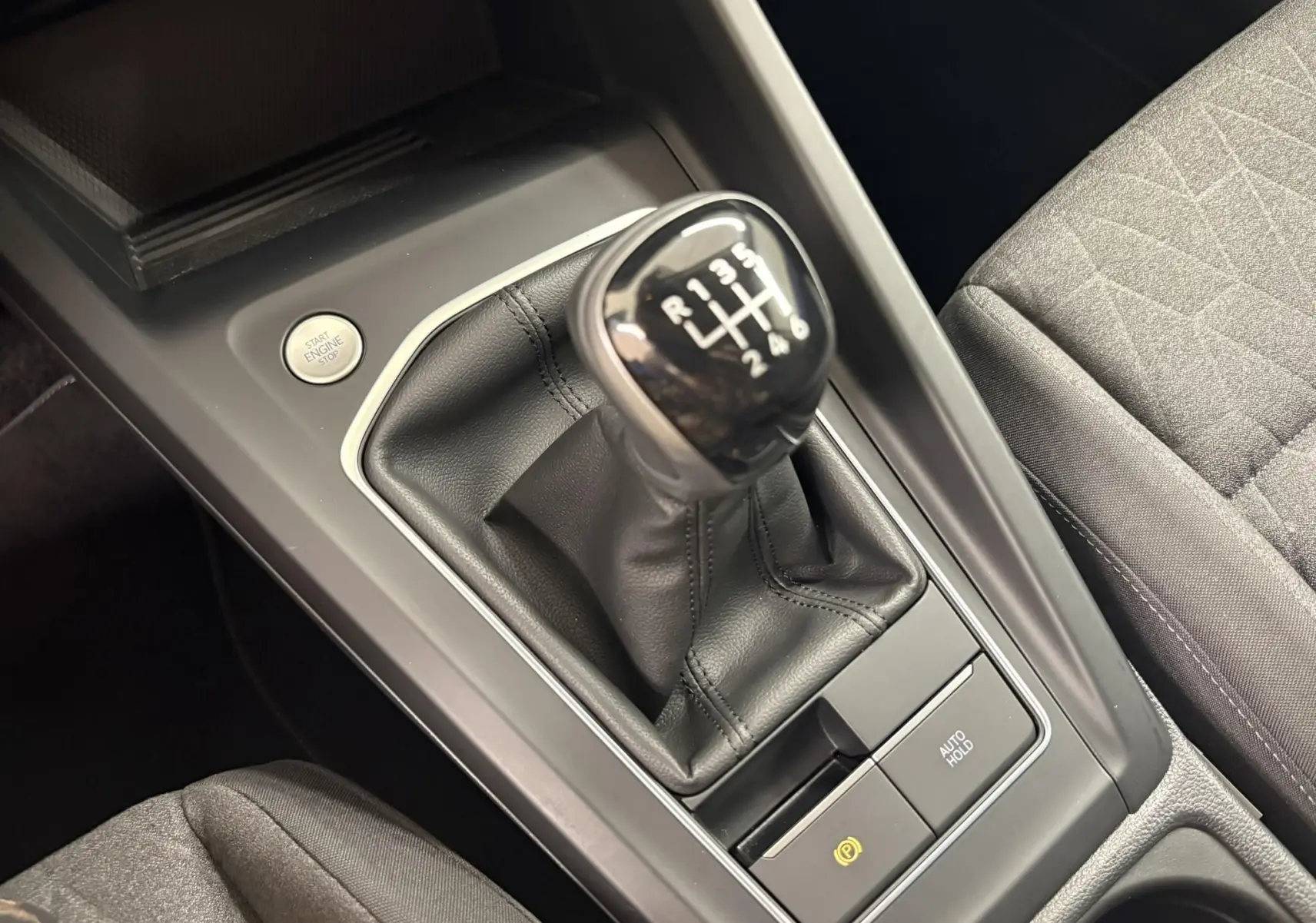 Gros plan sur la console centrale de la Volkswagen Golf 1.5 eTSI avec levier de vitesse manuelle et bouton Start/Stop.