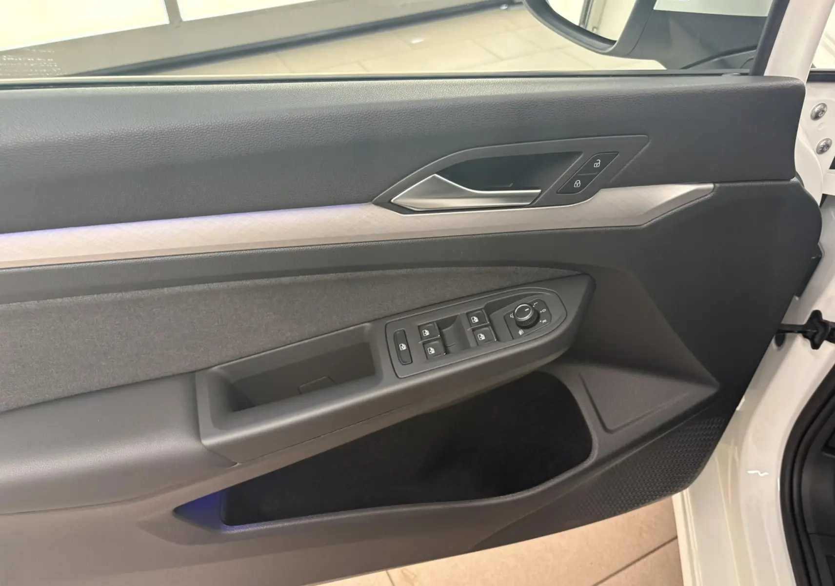 Intérieur côté gauche de la porte avant d'une Volkswagen Golf 2025 blanc Oryx nacré, avec commandes de vitres et serrure.