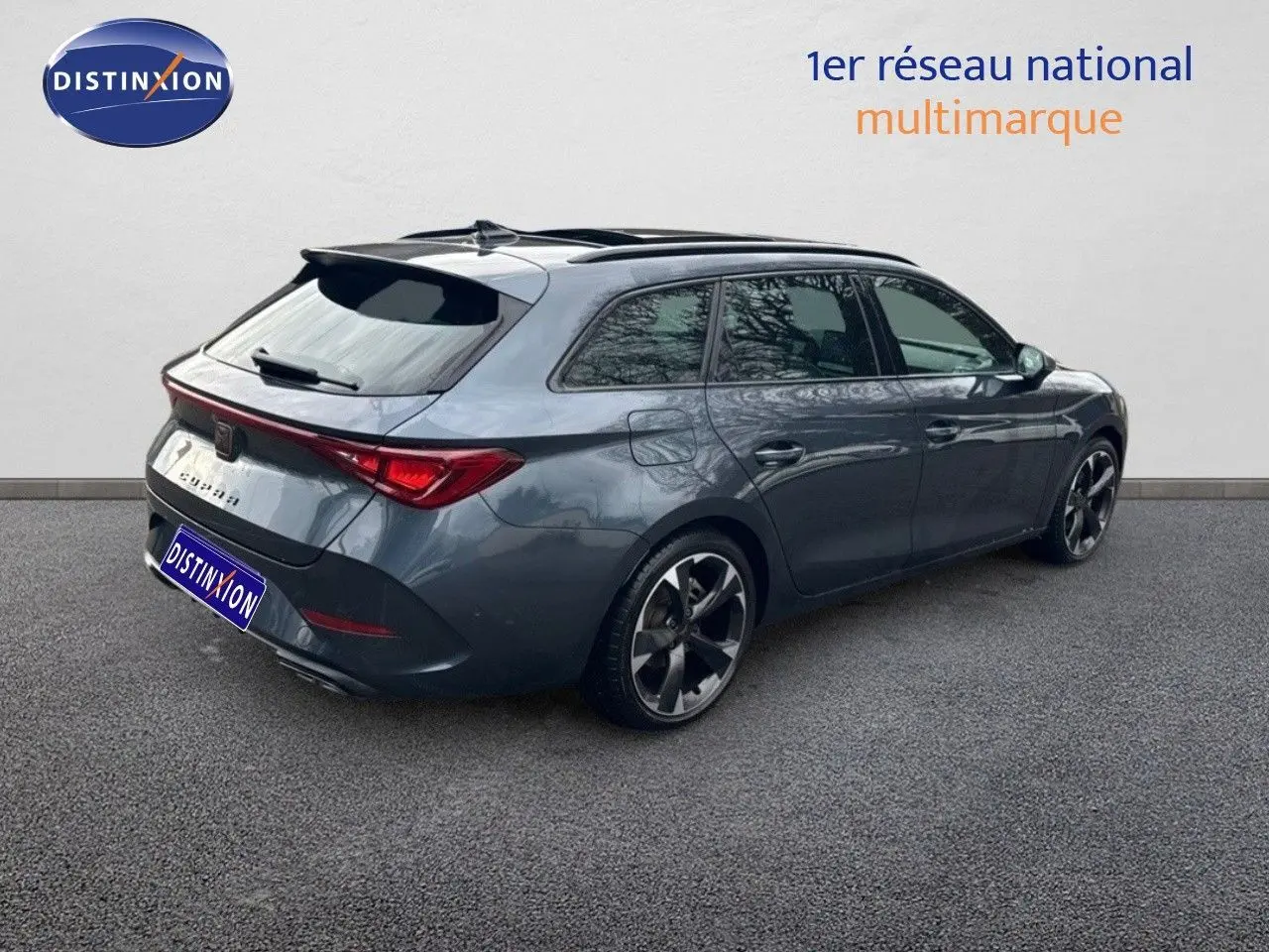 Vue 3/4 arrière droite d'une CUPRA LEON ST gris magnétique avec jantes bi-ton et feux arrière LED allumés.