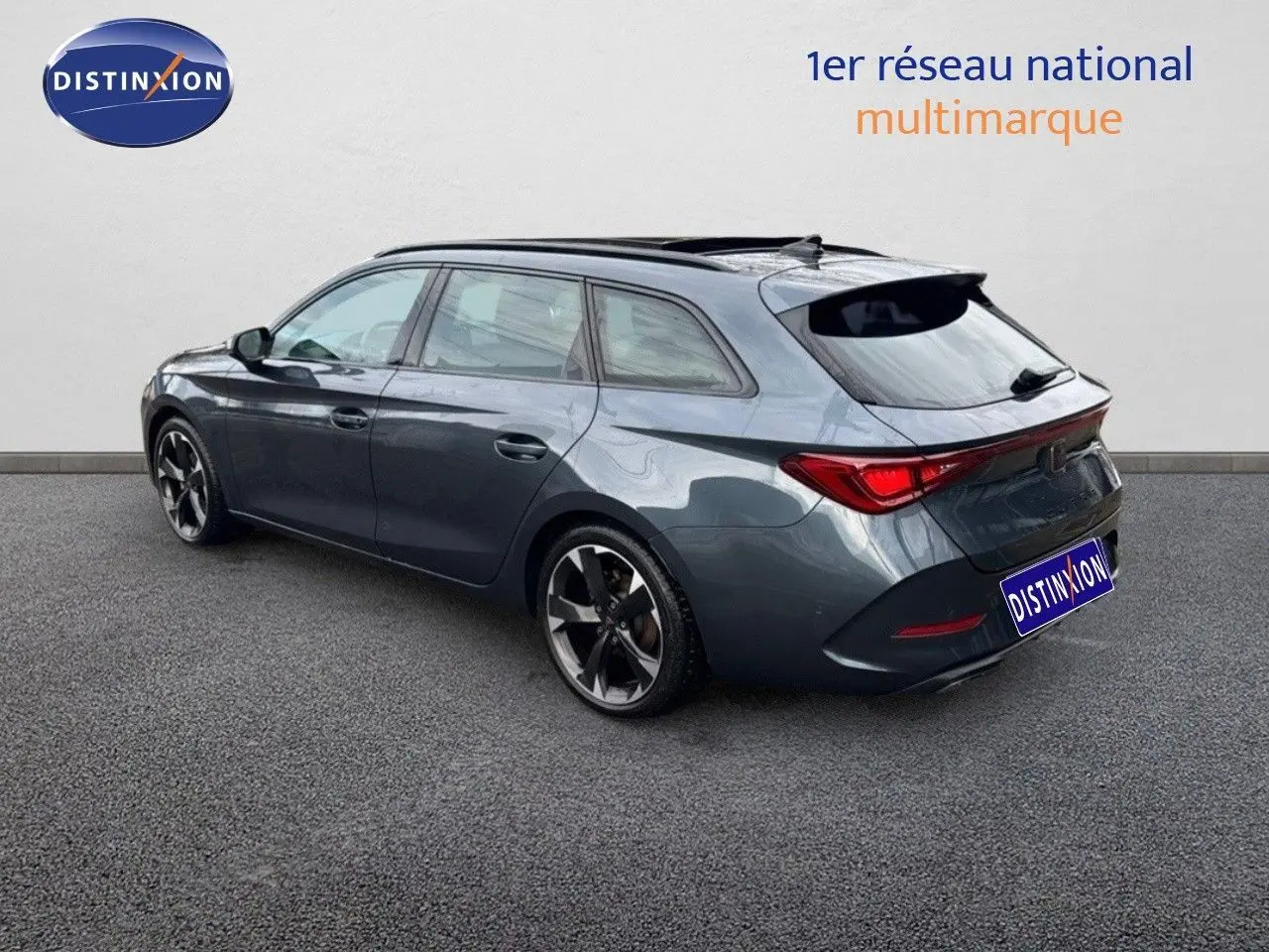 Vue 3/4 arrière droite d'une CUPRA LEON ST gris magnétique 2024 avec jantes bi-ton et toit ouvrant panoramique.
