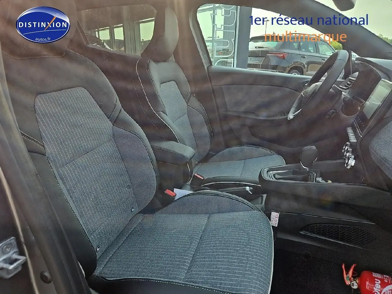 Intérieur avant de la Renault Clio V 1.6 e-tech 145 techno avec sièges sport gris et console centrale visible.