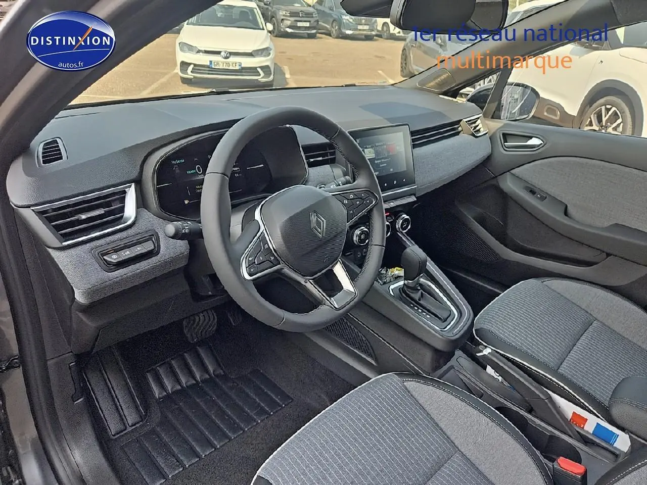 Intérieur de la Renault Clio V gris schiste, vue côté conducteur, volant multifonction et écran tactile central visibles.