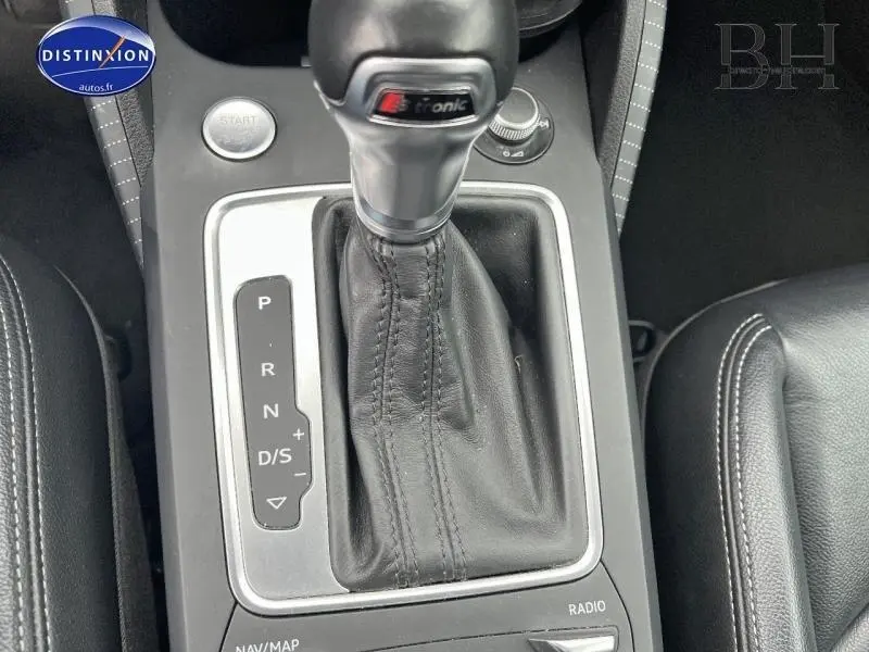 Le levier de vitesses automatique S tronic en cuir noir de l'Audi Q2 blanc Ibis vu de dessus, avec bouton start visible.