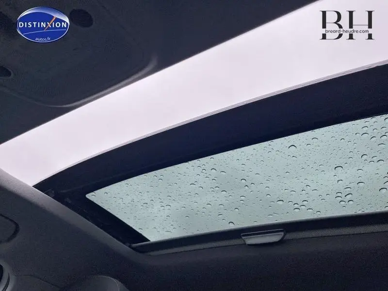 Toit ouvrant électrique coulissant du côté conducteur de l'Audi Q2 blanc Ibis, vue intérieure avec gouttes de pluie sur le verre.