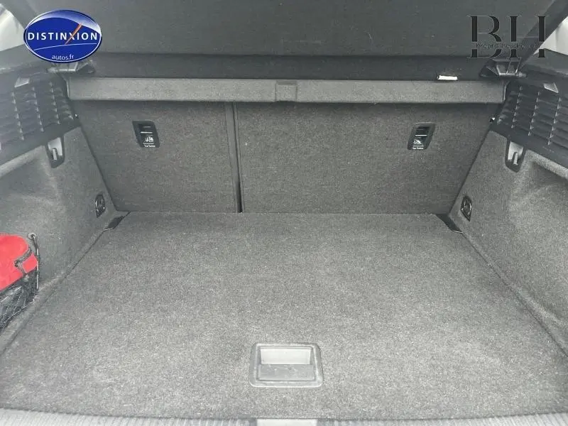 Coffre spacieux de l'Audi Q2 blanc Ibis, vue intérieure arrière avec revêtement gris et filet de rangement rouge à gauche.