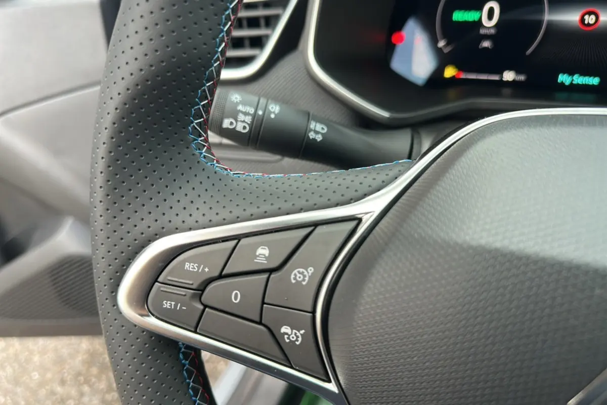 Gros plan sur le volant cuir perforé avec commandes multifonctions de la Renault Clio V E-Tech 145 Esprit Alpine Bose.