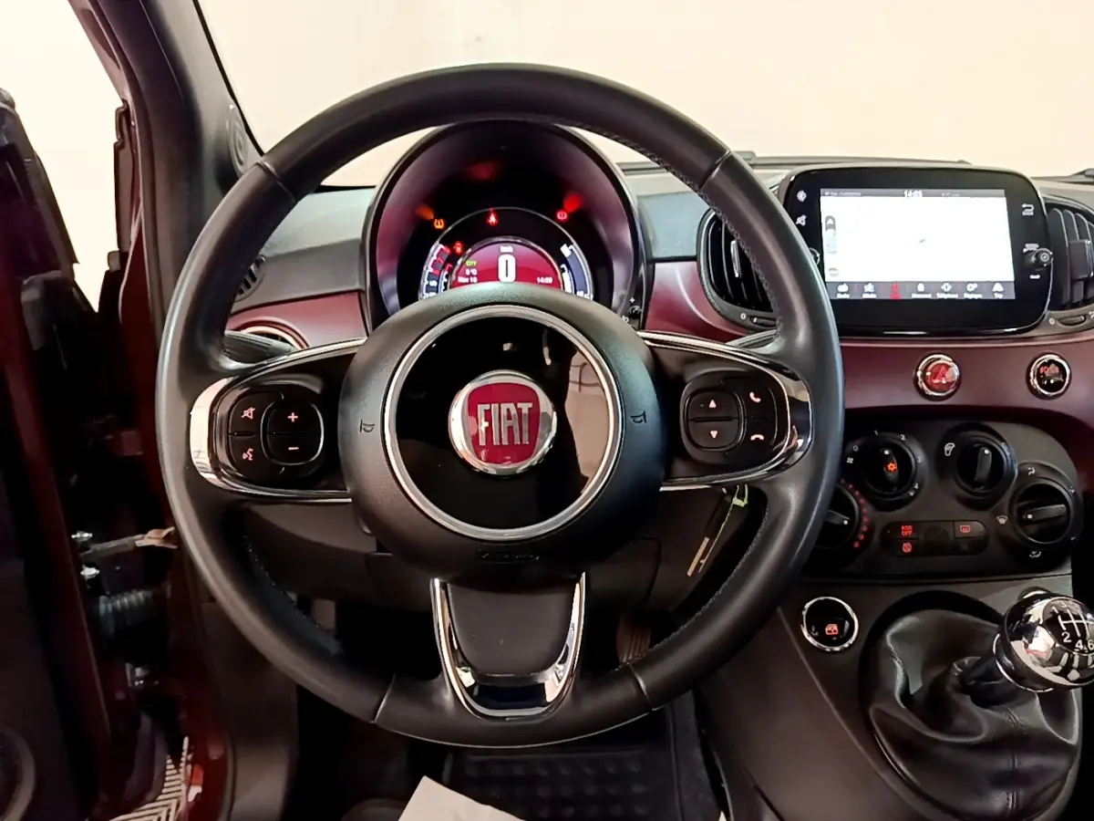 Vue intérieure centrée sur le volant cuir noir et tableau de bord rouge de la FIAT 500 1.0 70ch BSG Star 2021.