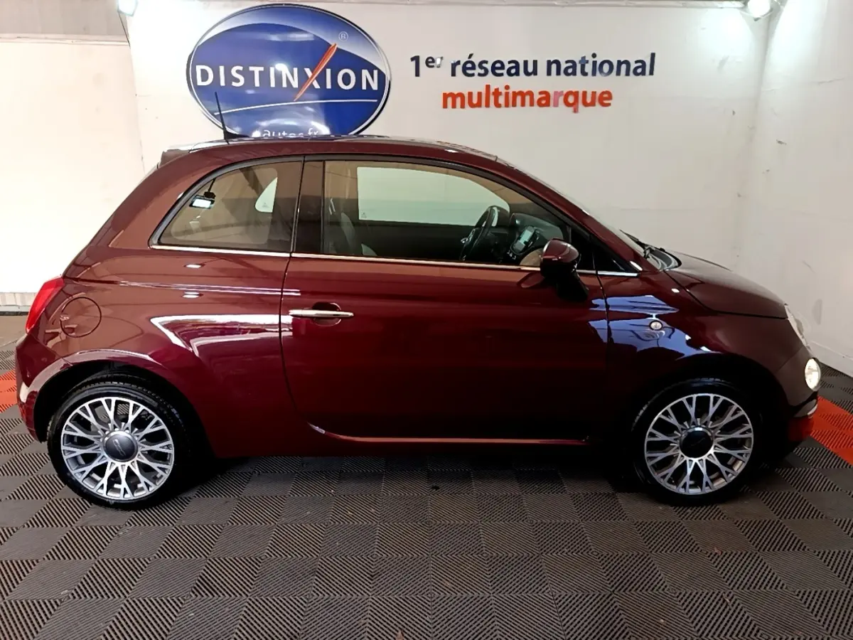 Profil droit d'une FIAT 500 rouge foncé 2021 avec jantes alliage et intérieur visible en arrière-plan.