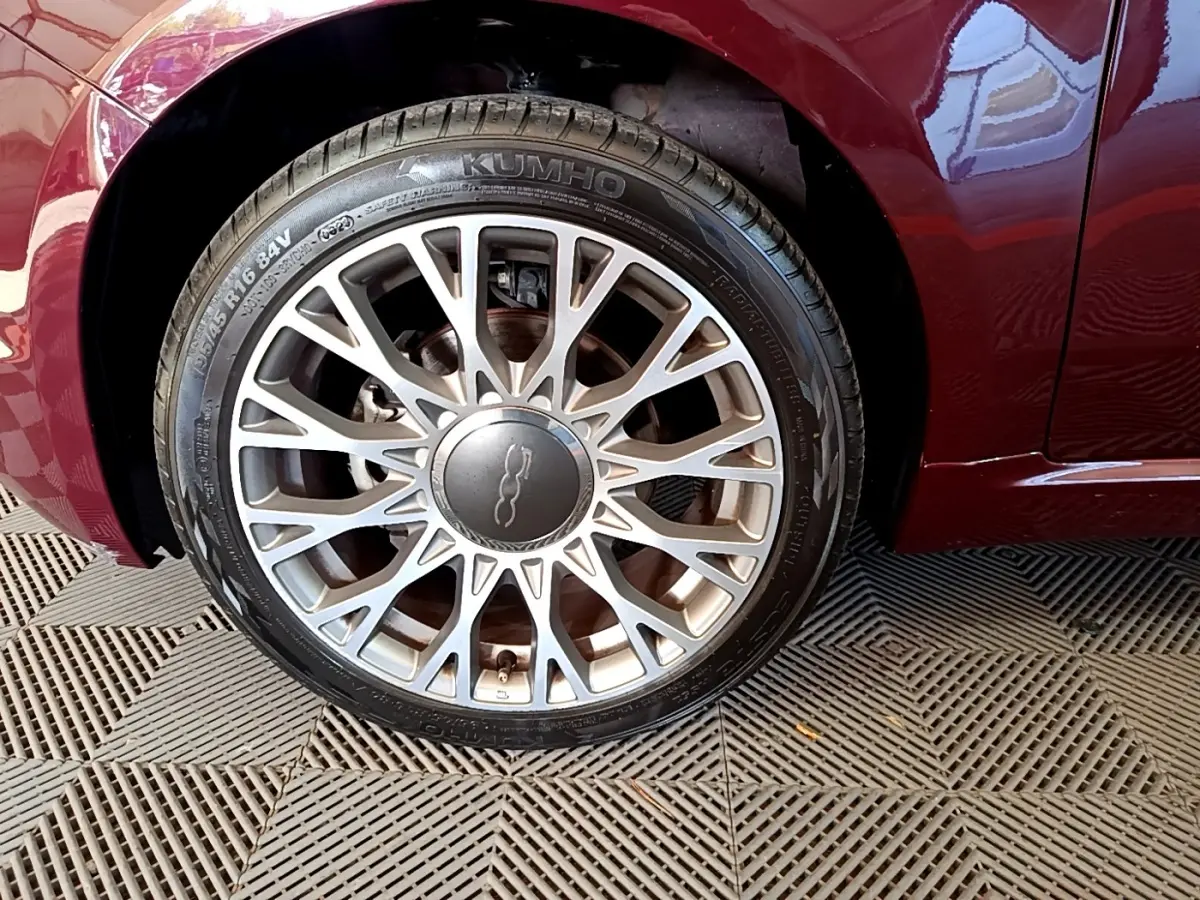 Gros plan sur la roue avant droite argentée de la FIAT 500 rouge, mettant en valeur la jante au design fin et ajouré.