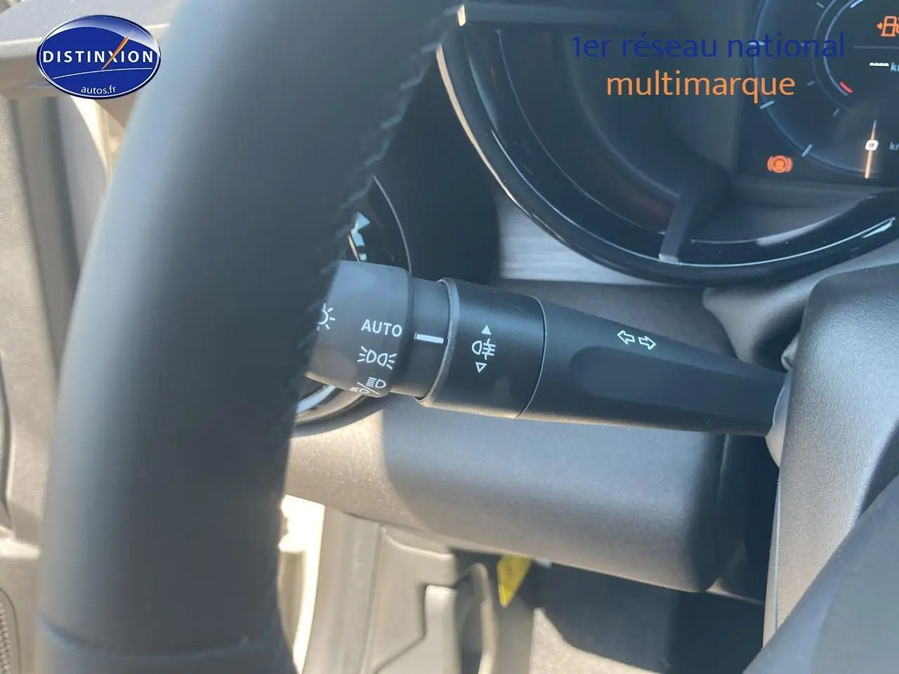 Gros plan sur la commande des feux et clignotants derrière le volant d’une Alfa Romeo Junior ivoire/noir.