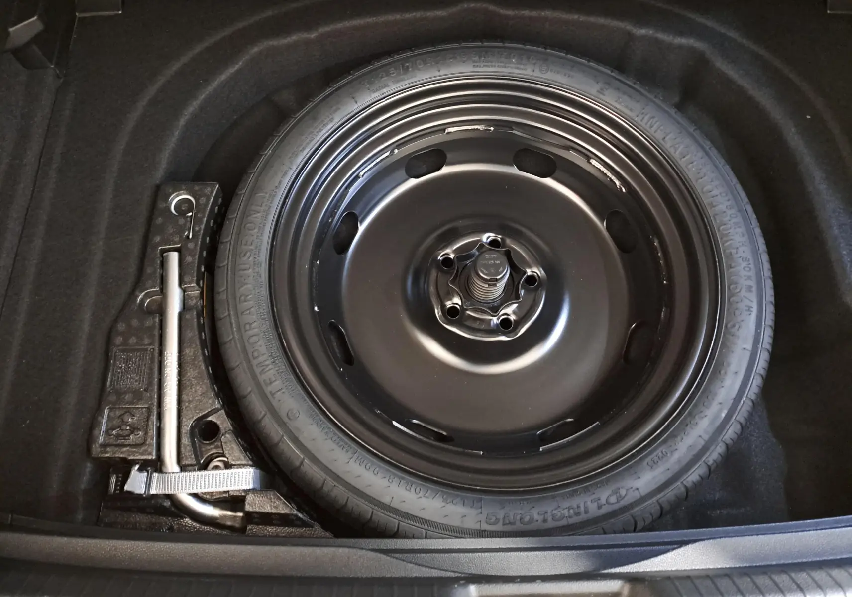 Roue de secours et cric dans le coffre d'une Volkswagen Golf 1.5 eTSI 116 DSG7 Bleu Glacier, vue de dessus.
