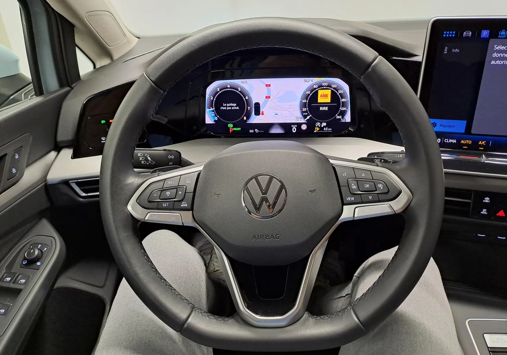 Vue intérieure centrée sur le volant multifonction d'une Volkswagen Golf 2025, tableau de bord numérique visible.