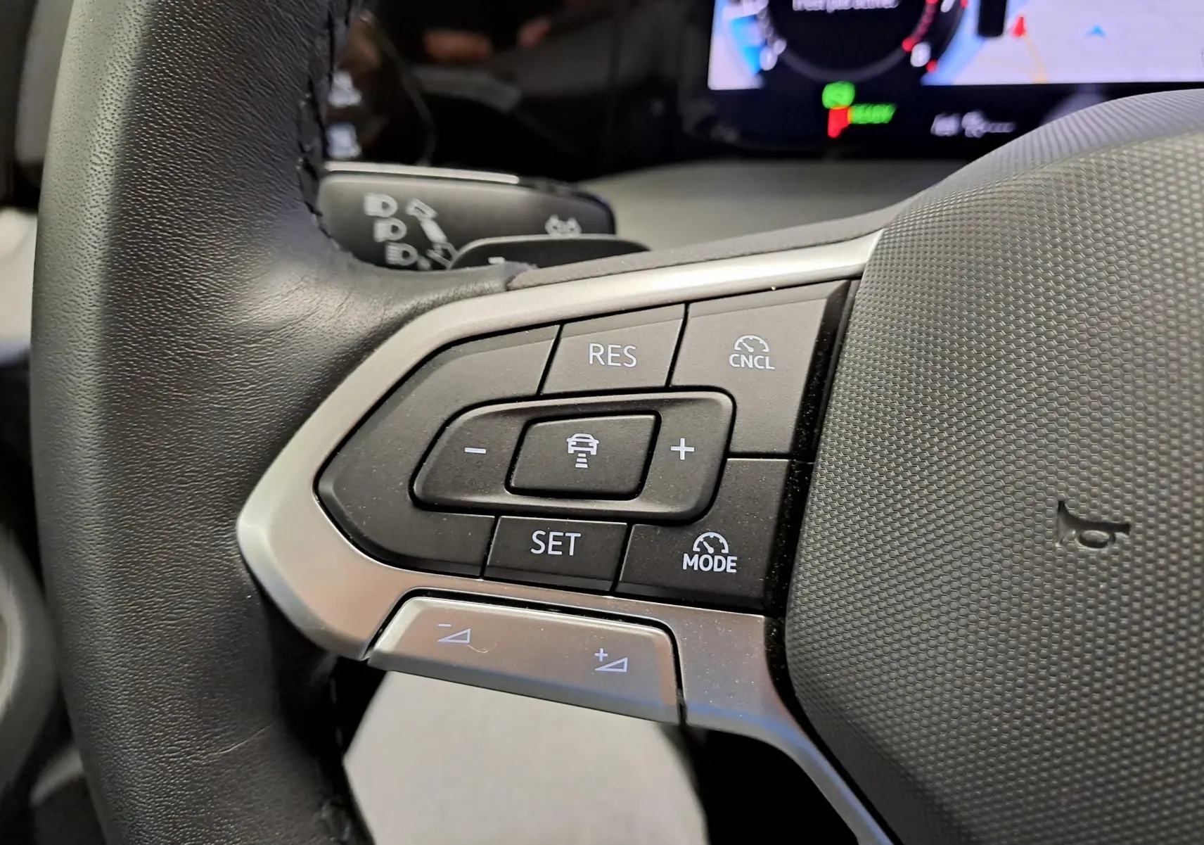 Gros plan sur les commandes du volant côté gauche d’une Volkswagen Golf Bleu Glacier 2025, avec régulateur de vitesse adaptatif.