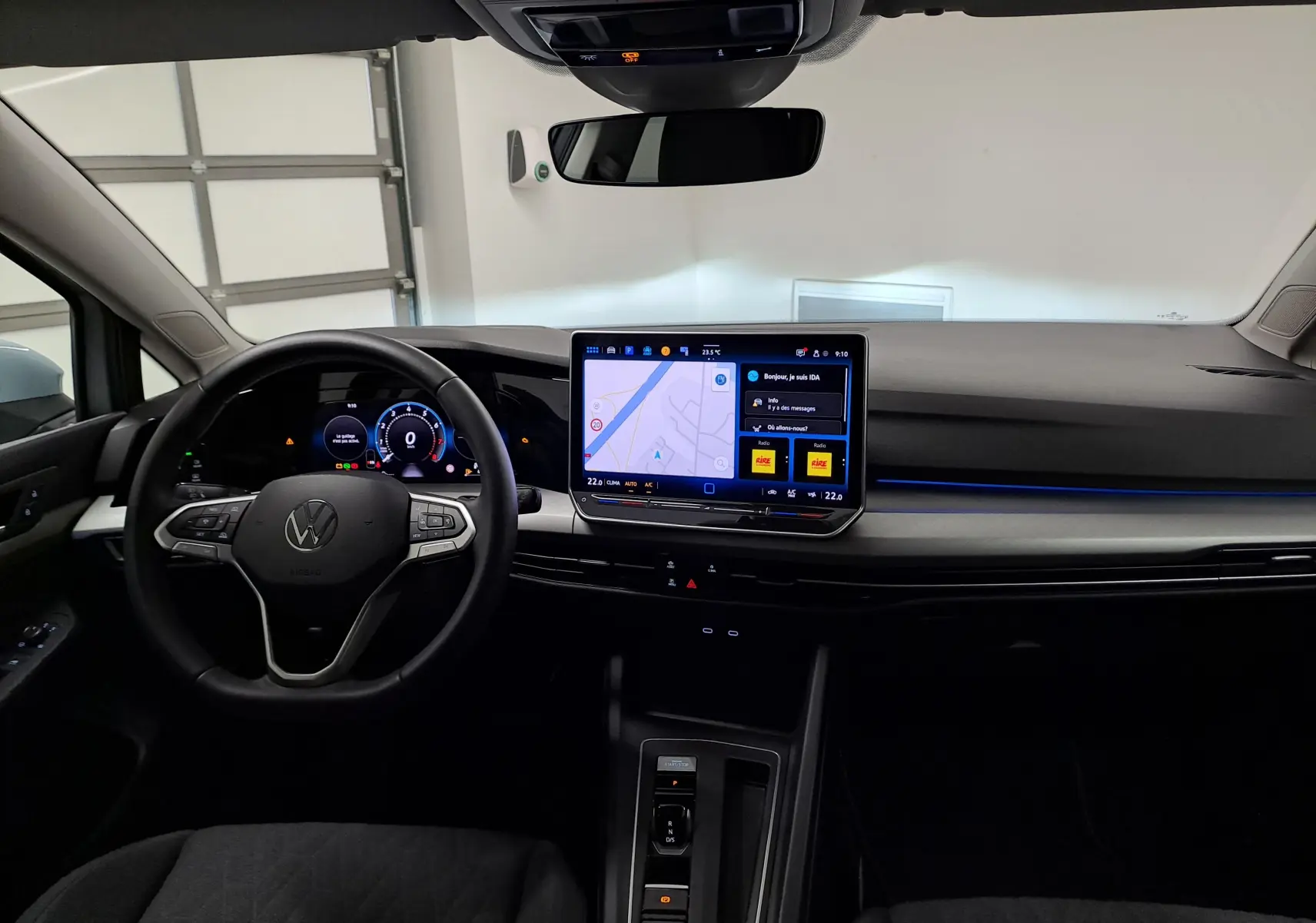 Intérieur de la Volkswagen Golf 1.5 eTSI 2025, vue du poste de conduite avec écran tactile central et volant multifonction.