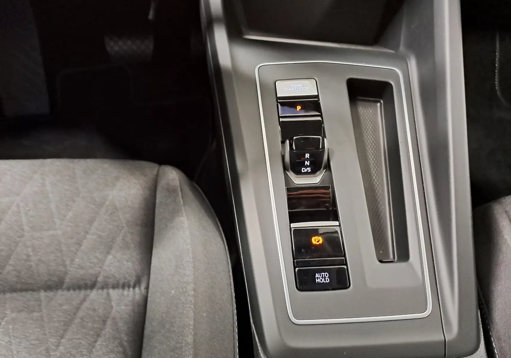 Vue rapprochée de la console centrale de la Volkswagen Golf 1.5 eTSI 116 DSG7, avec levier de vitesses automatique et siège tissu gris.