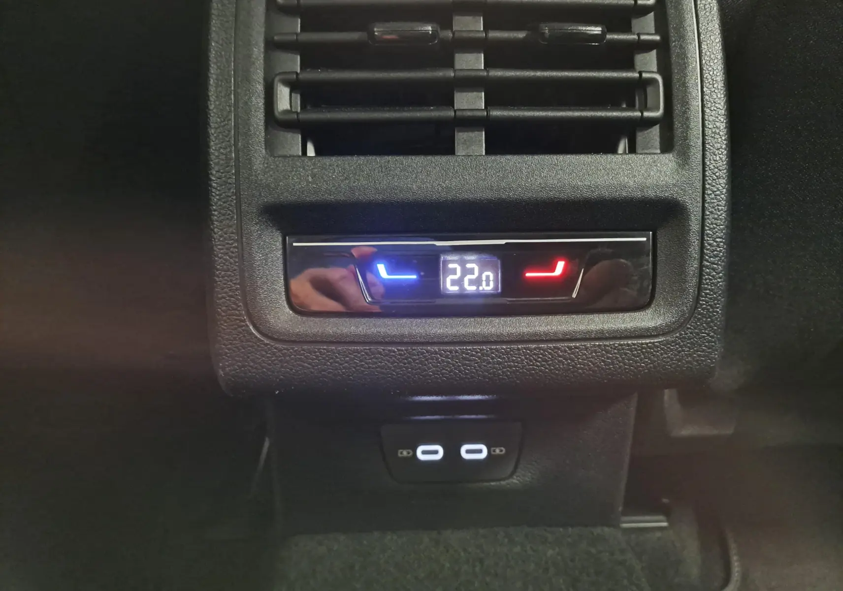 Détail du contrôle de climatisation arrière avec affichage digital à 22°C et ports USB-C dans une Volkswagen Golf Bleu Glacier.