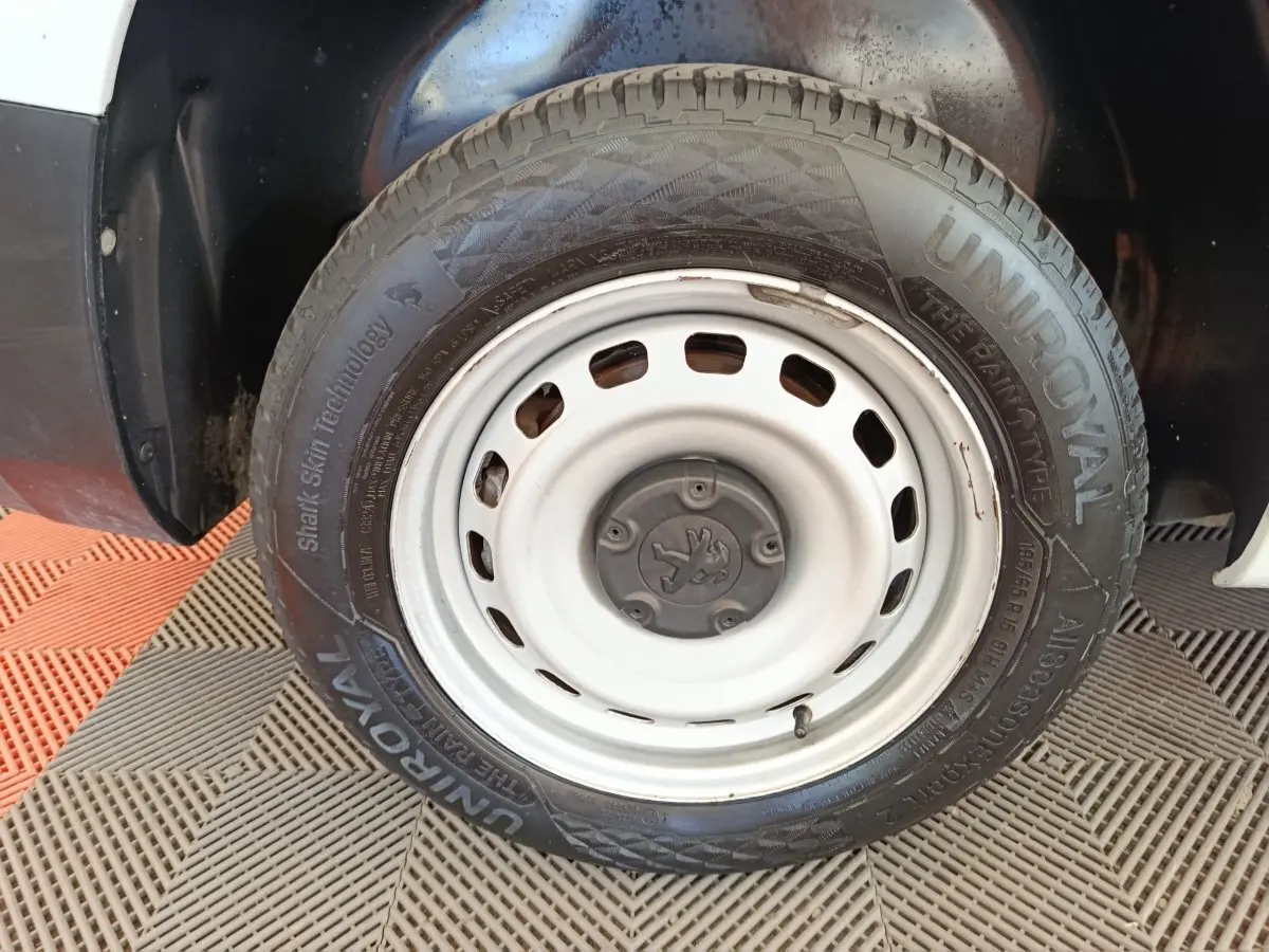 Gros plan sur la roue avant droite blanche du Peugeot Partner 2022 avec jante acier et pneu Uniroyal.