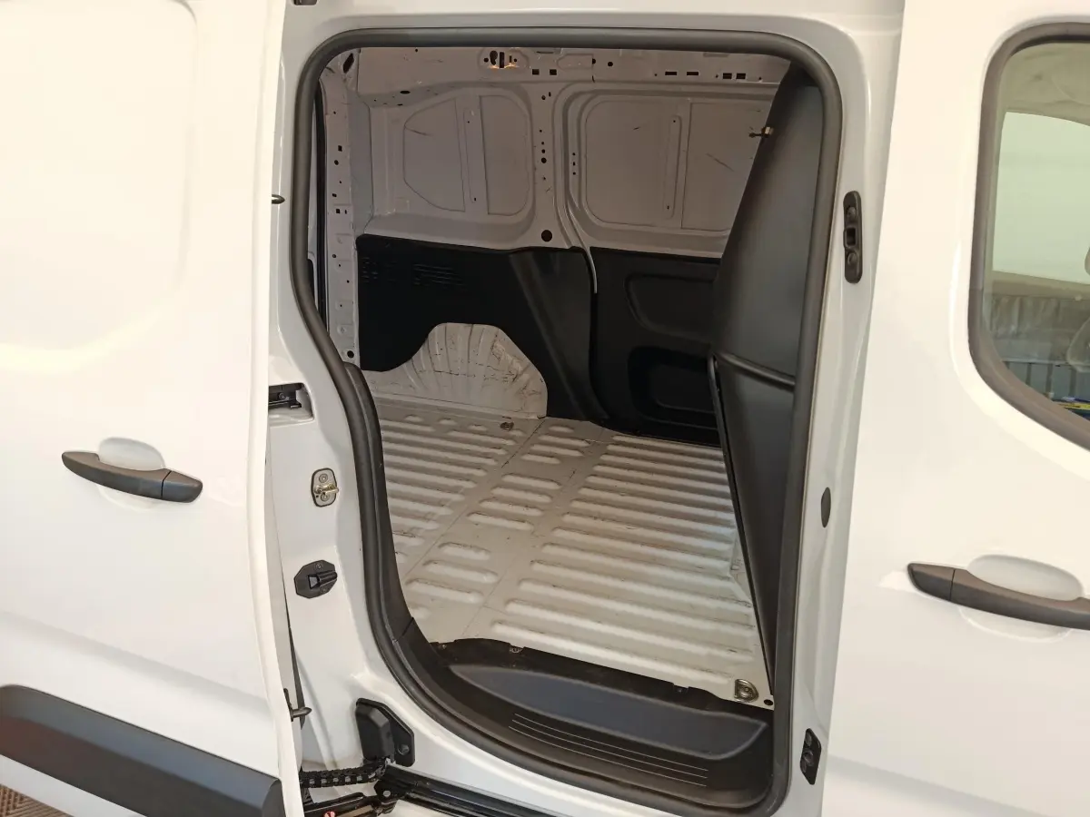 Vue latérale droite du Peugeot Partner blanc 2022 avec porte coulissante ouverte montrant l'espace de chargement vide.