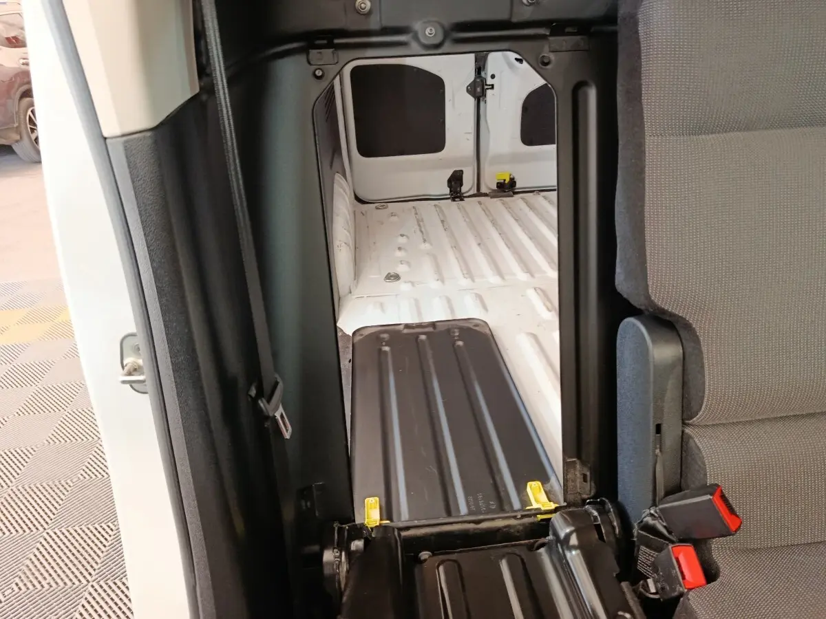 Vue intérieure du compartiment de chargement blanc du Peugeot Partner Taille M, avec cloison pleine et siège rabattable gris.