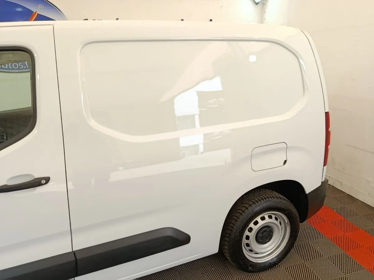 Vue latérale droite d’un utilitaire Peugeot Partner blanc, mettant en valeur la cloison pleine et la roue arrière acier.