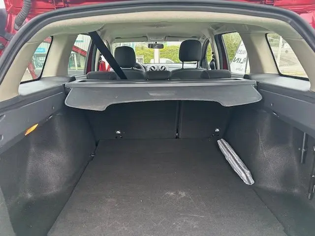 Vue depuis l'arrière du coffre ouvert d'une Dacia Logan MCV rouge, montrant l'espace de chargement avec cache-bagages déployé.