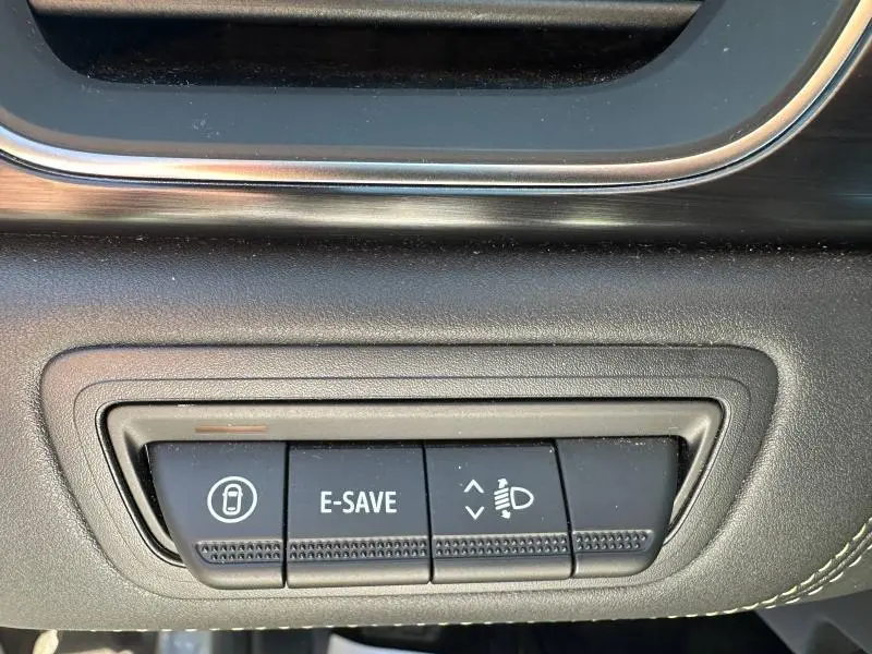Gros plan sur les boutons de commande noirs du tableau de bord de la Renault Symbioz rouge, avec fonction E-SAVE visible.