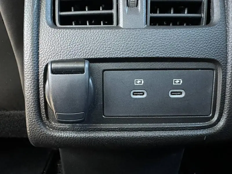 Prise USB-C double et prise 12V noire en gros plan sur la console arrière du Renault Symbioz rouge.