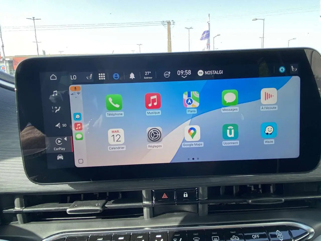 Écran tactile central affichant Apple CarPlay dans l'habitacle d'une Fiat 500 Electrique noire, vue de face.