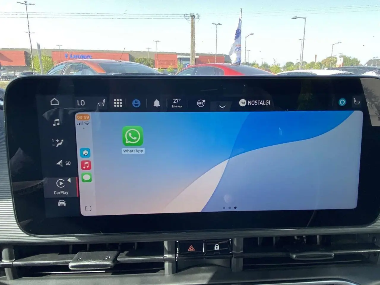 Écran tactile central de la Fiat 500 électrique 2022 affichant Apple CarPlay avec l'application WhatsApp ouverte.