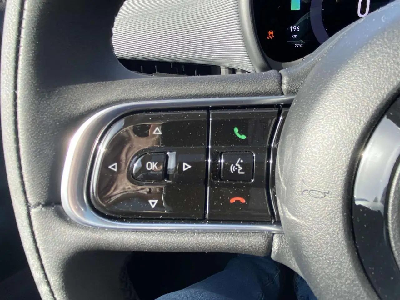 Gros plan sur les commandes au volant noir de la Fiat 500 électrique 2022 avec tableau de bord numérique visible.