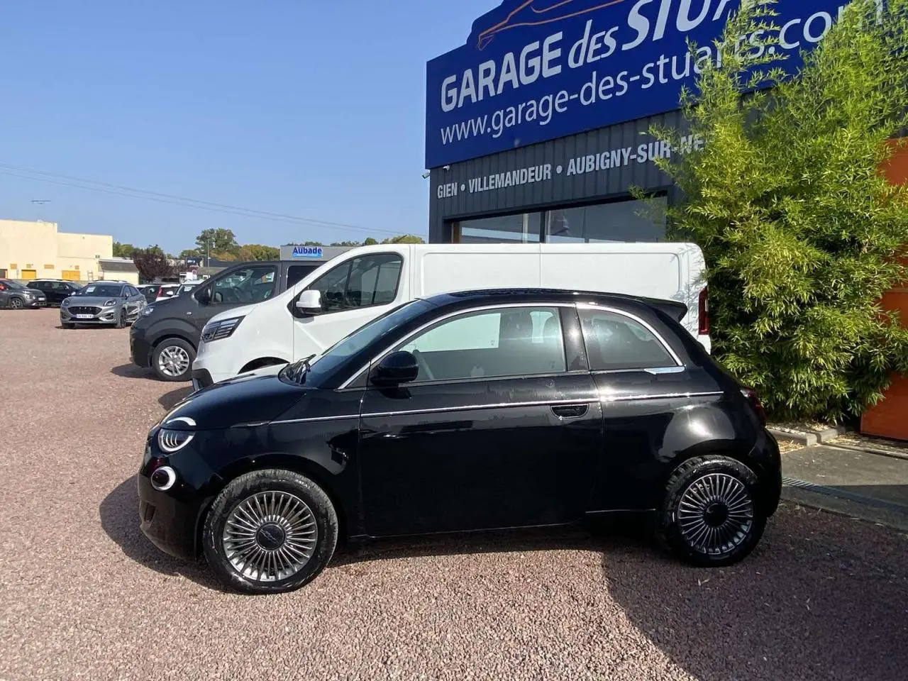 Profil côté gauche de la Fiat 500 électrique noire métal 2022 avec jantes stylisées et baguettes chromées visibles.