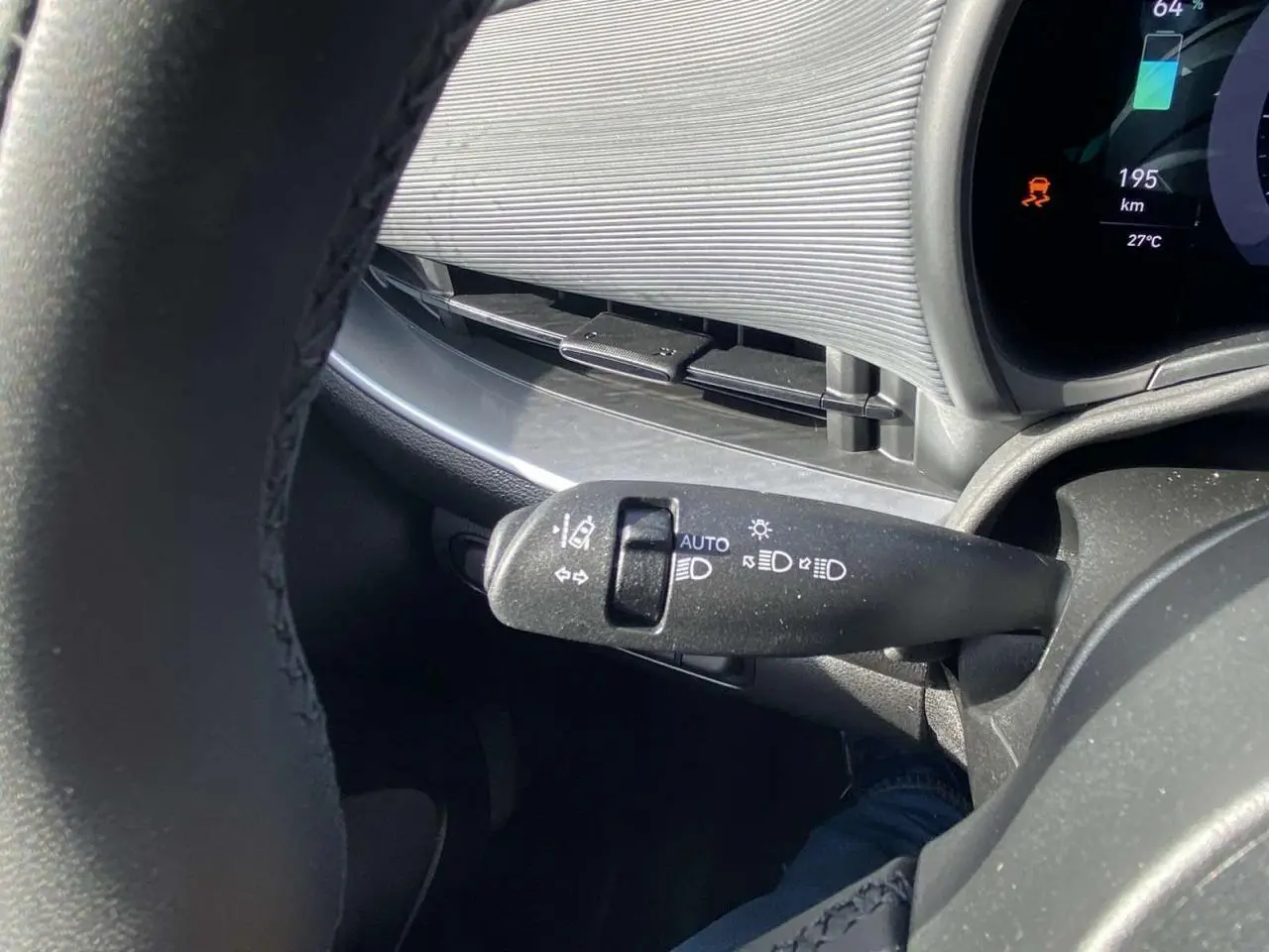 Gros plan sur la commande des feux au volant d'une Fiat 500 électrique 2022, planche de bord Technowood visible.