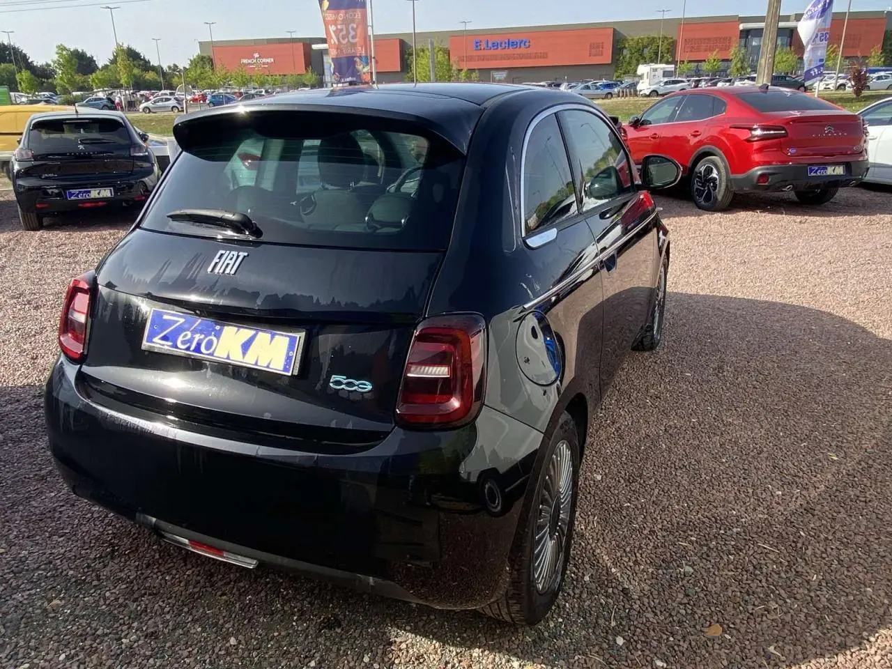 Vue 3/4 arrière droite de la Fiat 500 Electrique noire métal avec badge 500 et prise de recharge visible sur le côté.