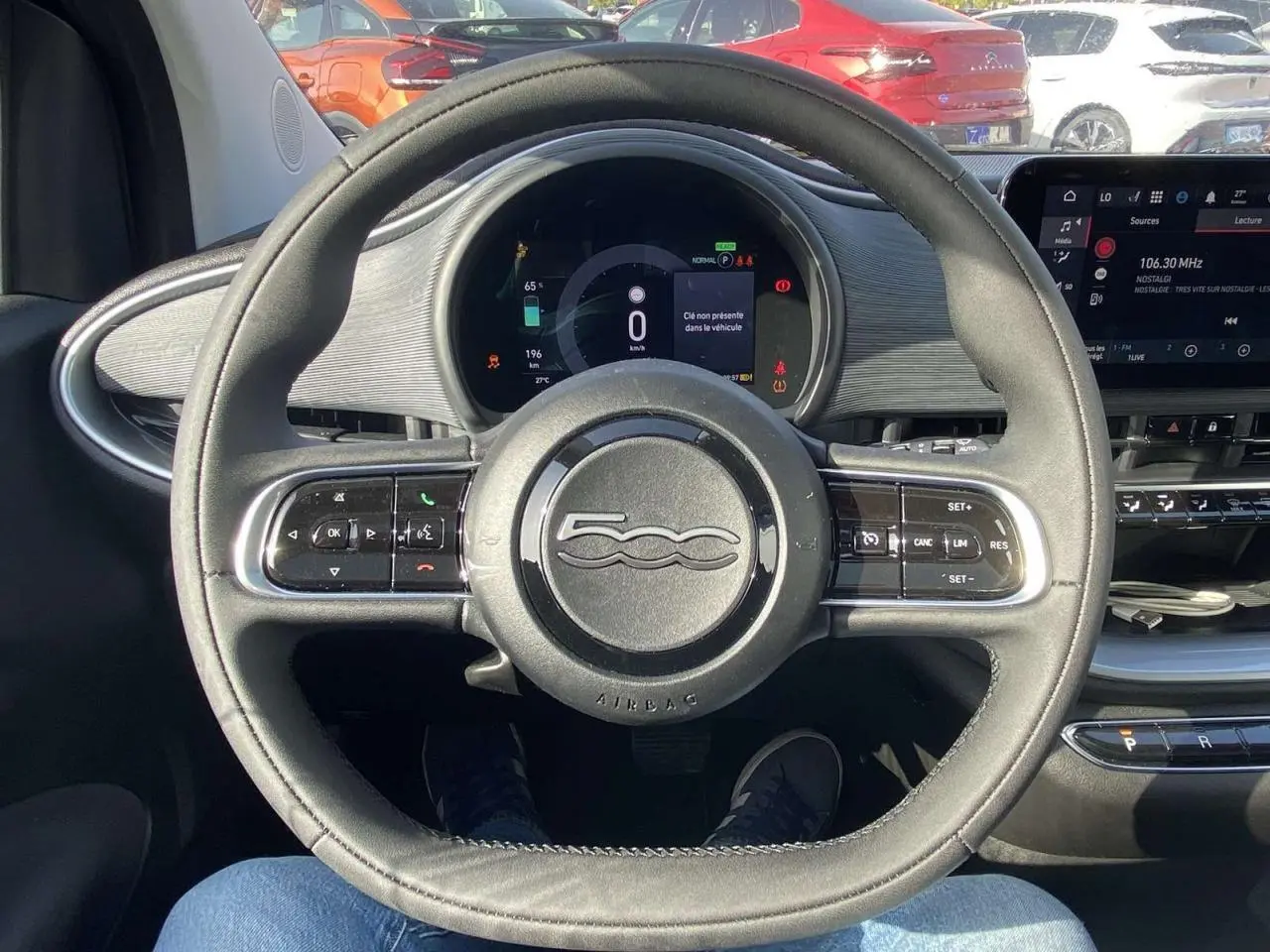 Vue intérieure centrée sur le volant noir de la Fiat 500 électrique avec tableau de bord numérique et écran tactile.