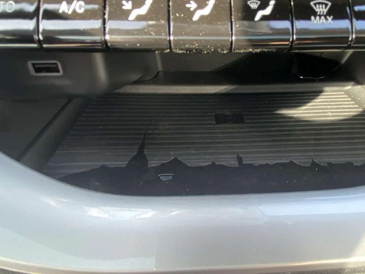 Gros plan sur la console centrale noire avec commandes climatisation et surface de recharge sans fil dans une Fiat 500 Electrique noire.