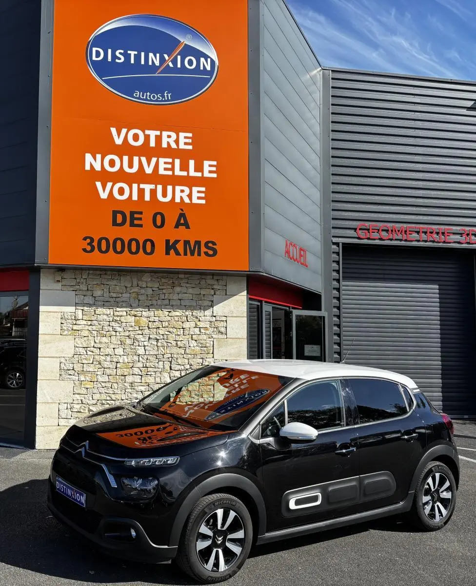 Citroën C3 PureTech 110 BVM6 Max noir avec toit blanc vue 3/4 avant, stationnée devant un panneau orange Distinxion.