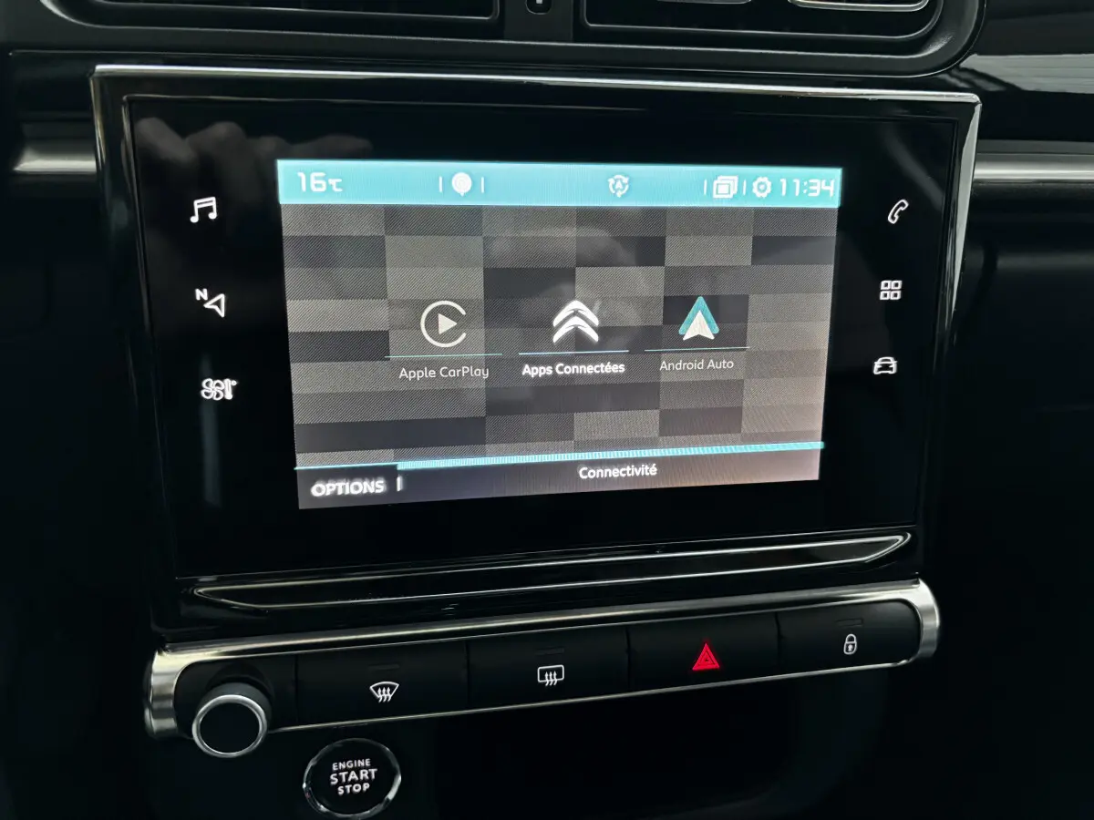 Écran tactile central affichant Apple CarPlay et Android Auto dans le tableau de bord noir d'une Citroën C3 2024.