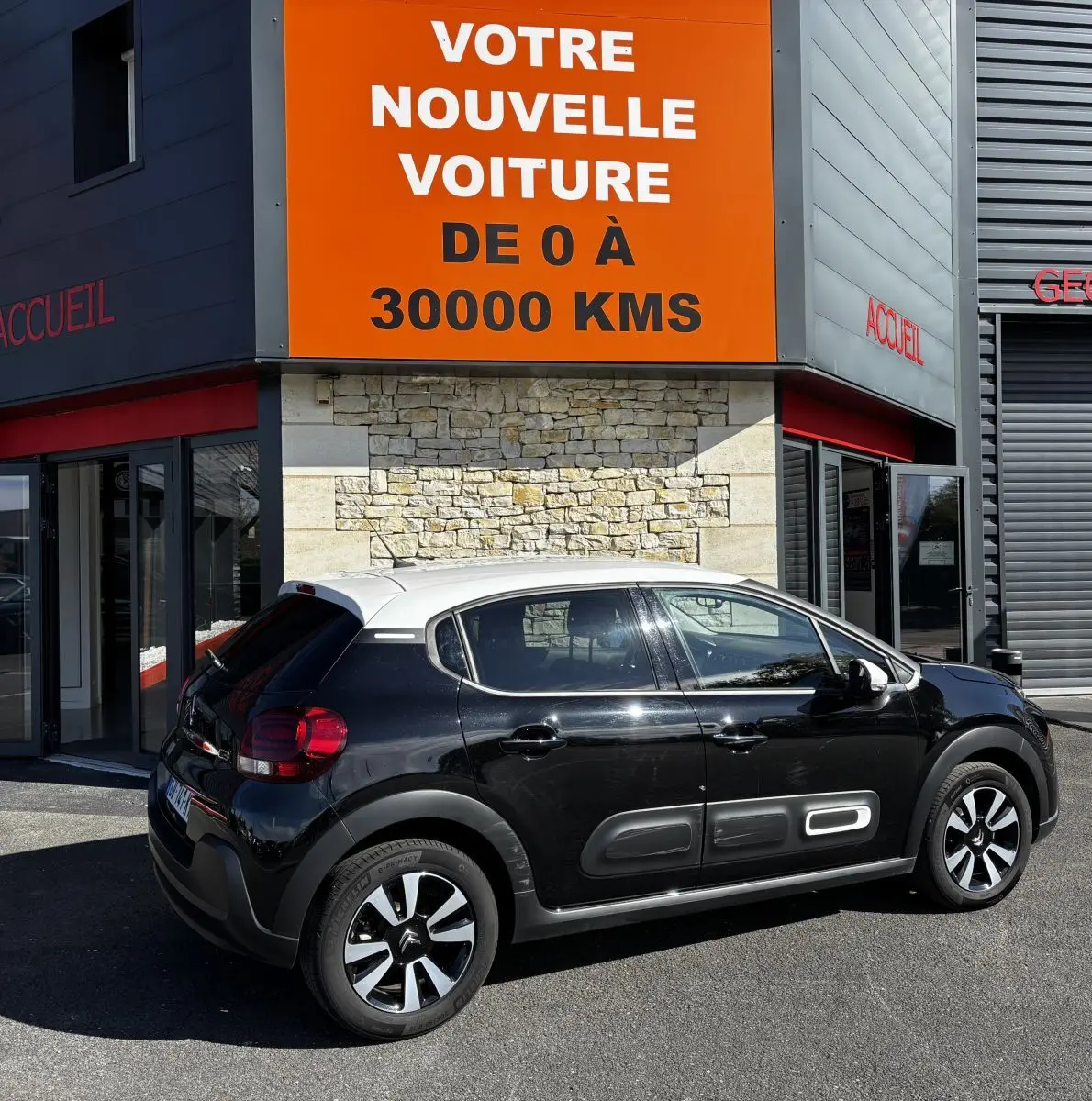 Vue côté gauche arrière d'une Citroën C3 bicolore noir et toit blanc avec protections latérales caractéristiques.