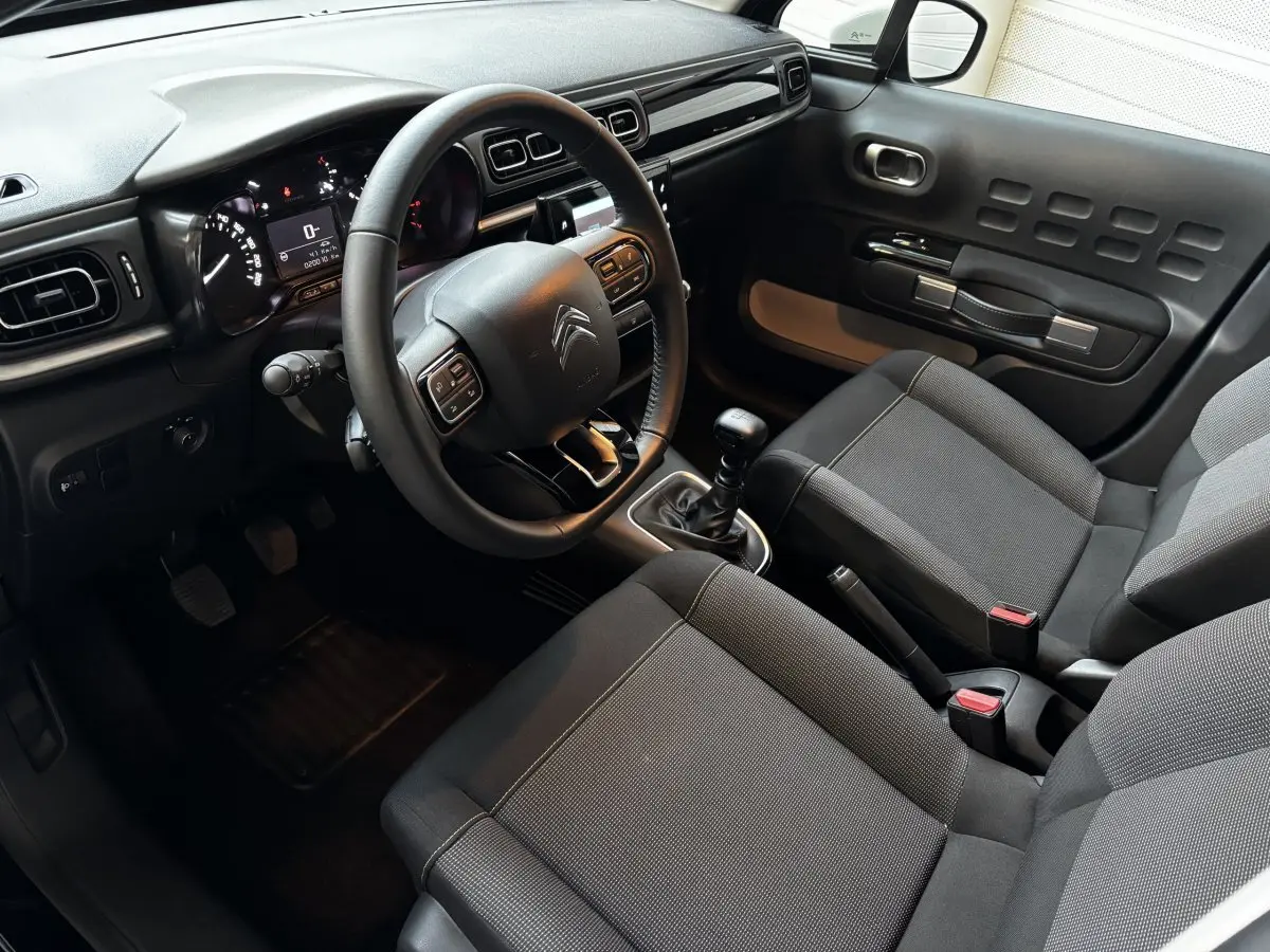 Vue intérieure côté conducteur de la Citroën C3 gris clair 2024 avec tableau de bord moderne et boîte manuelle.