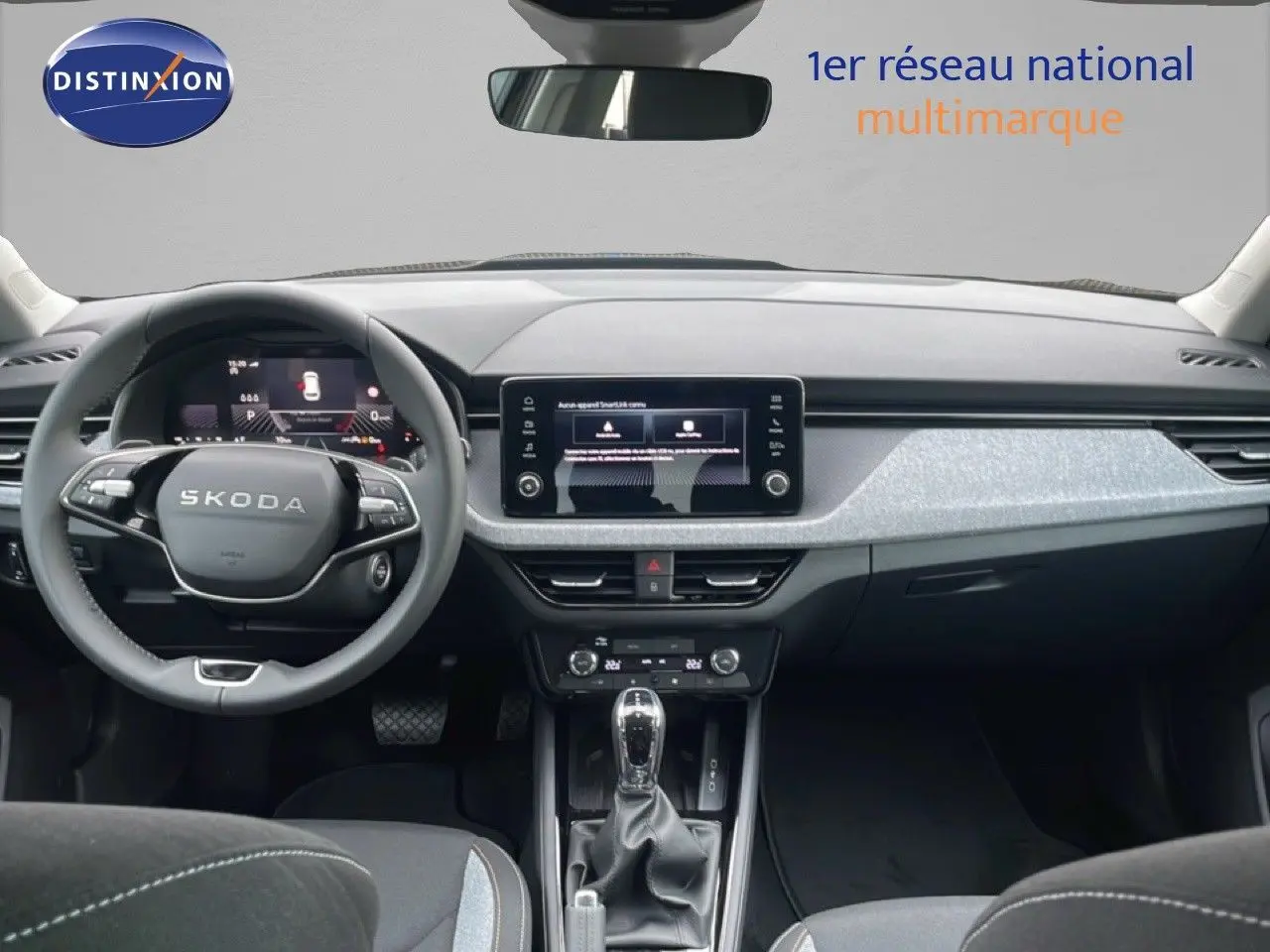 Vue intérieure frontale du tableau de bord et volant Skoda Kamiq noir, avec écran tactile central et levier de vitesse automatique.