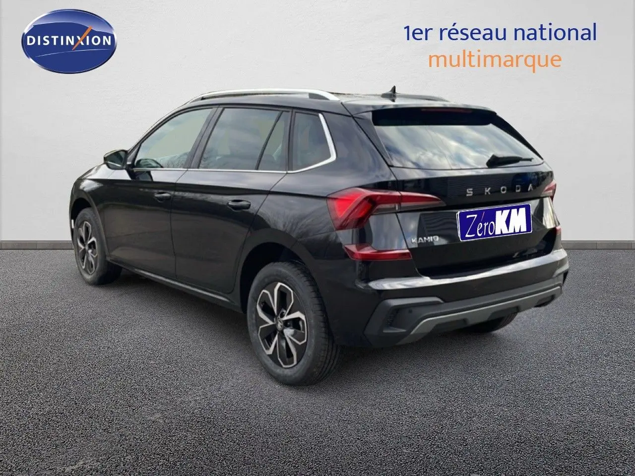 Vue 3/4 arrière droite d'un Skoda Kamiq noir magique métal avec jantes bi-ton et toit équipé de barres de toit.