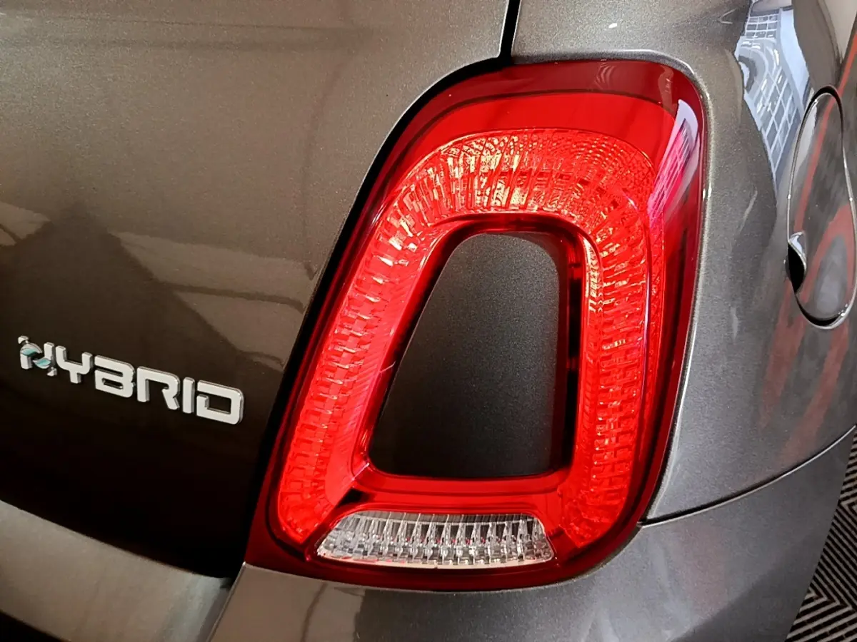 Gros plan sur le feu arrière droit rouge et le logo Hybrid d'une FIAT 500 gris foncé vue de l'arrière.
