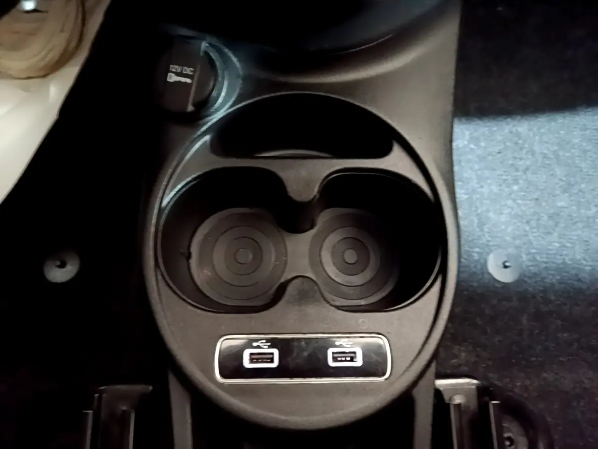 Gros plan sur le porte-gobelets central avec prises USB doubles dans l'habitacle d'une FIAT 500 gris foncé.