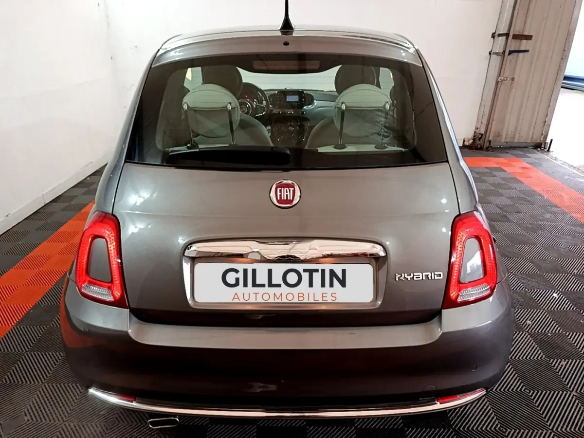 Vue arrière d'une FIAT 500 Hybrid gris foncé, avec feux LED et logo distinctif sur un sol à damiers noir et rouge.