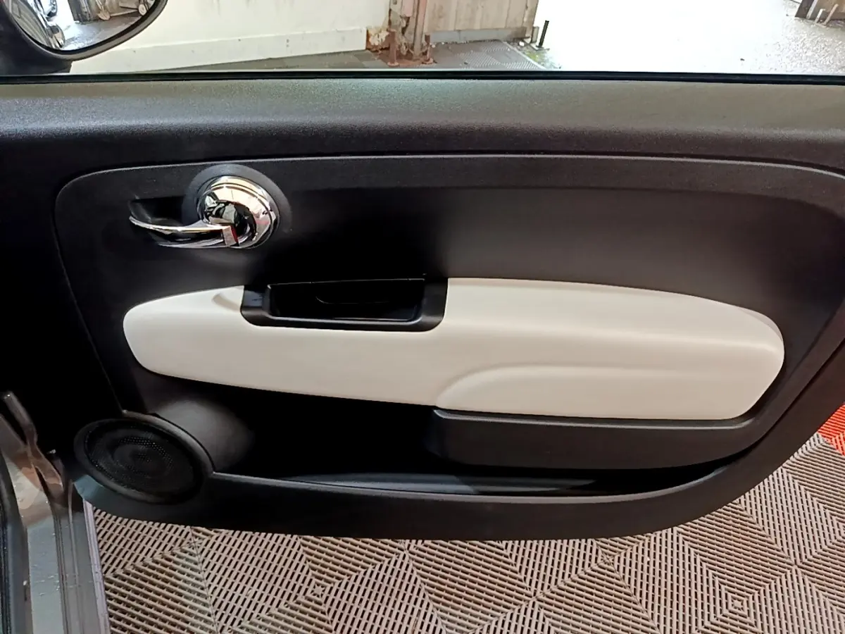 Gros plan sur la porte intérieure côté gauche de la FIAT 500 Dolcevita 2021 avec insert beige et poignée chromée.