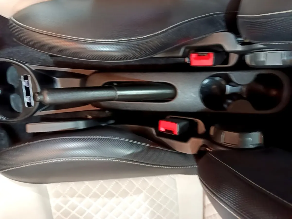 Vue plongeante sur la console centrale de la Fiat 500 Dolcevita, montrant frein à main et sièges en cuir noir.