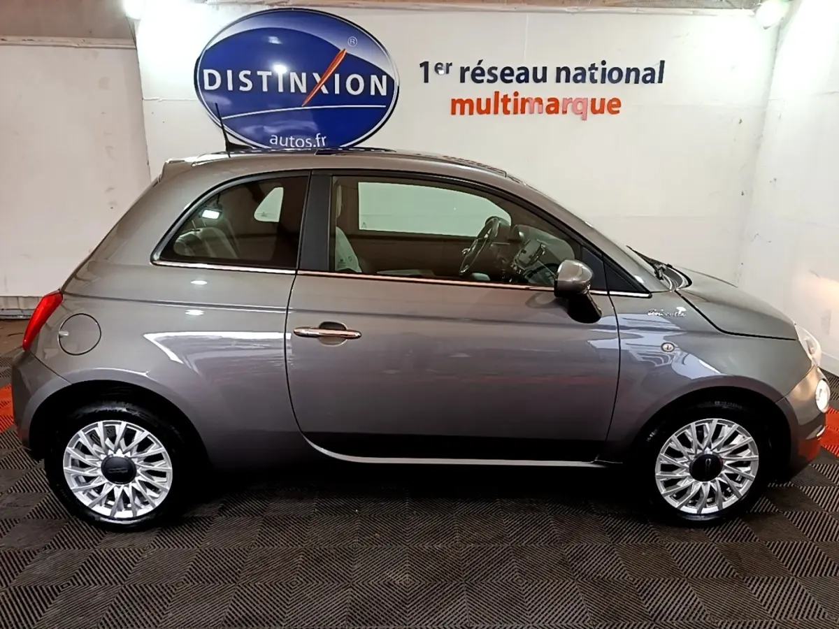 Profil côté gauche d'une FIAT 500 Hybrid gris foncé, avec jantes alliage et intérieur visible en arrière-plan.