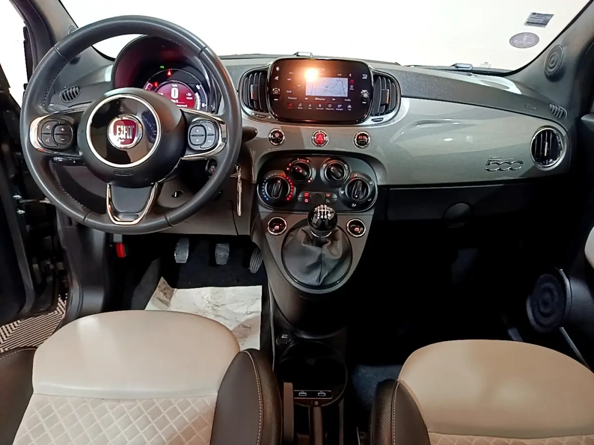 Vue intérieure frontale du tableau de bord gris clair et volant cuir noir de la Fiat 500 Hybrid 2021 avec écran tactile central.