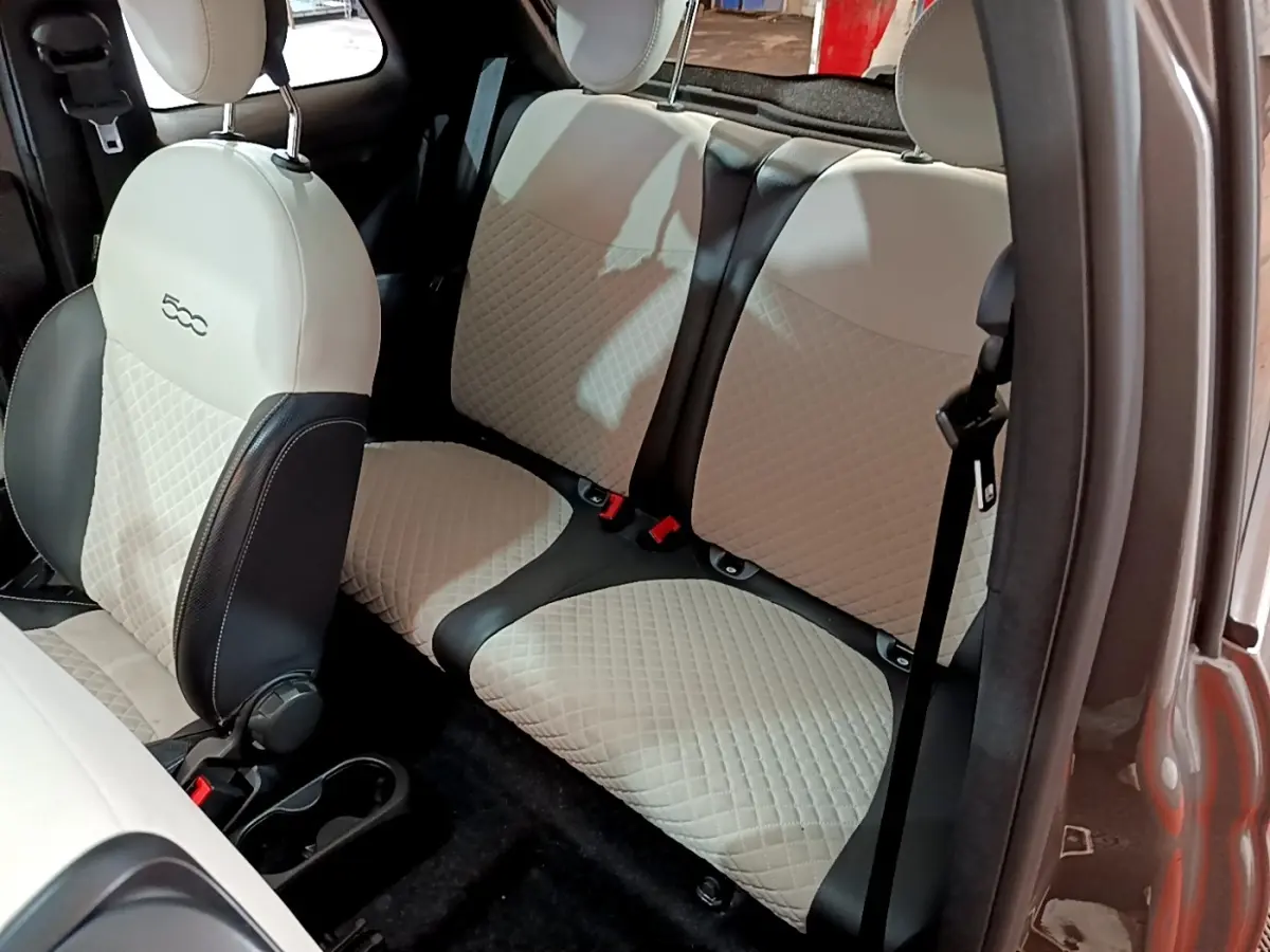 Vue intérieure sur les sièges arrière et avant beige matelassés de la Fiat 500 gris foncé, version Hybrid Dolcevita.