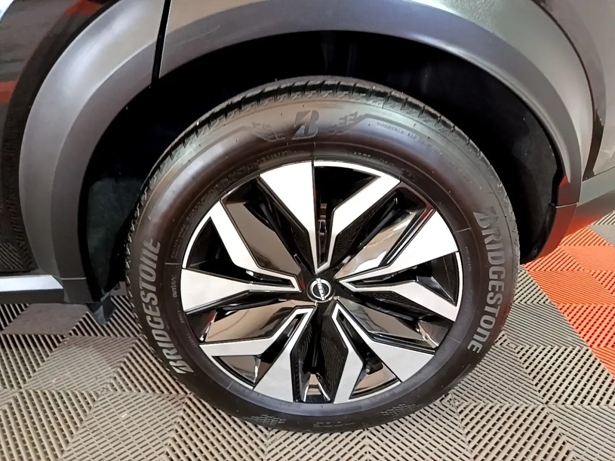 Gros plan sur la roue avant droite noire du Nissan Juke 2023 avec jante alliage bicolore et pneu Bridgestone.